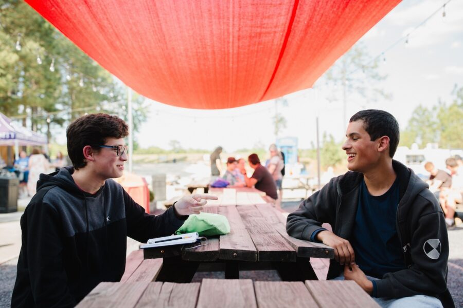 Two students talking at a picnic table outside