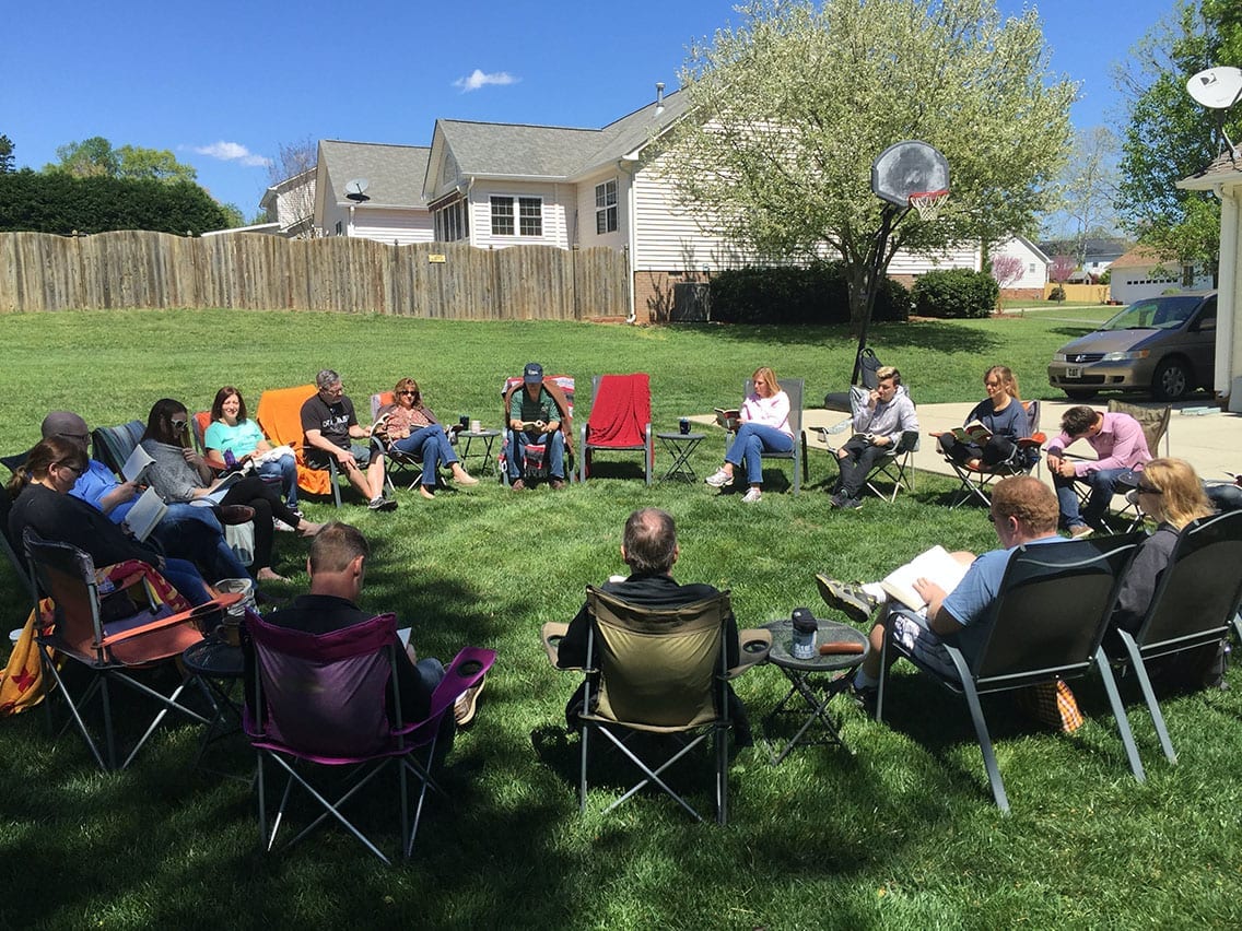people sitting outside in a circle of lawn chairs