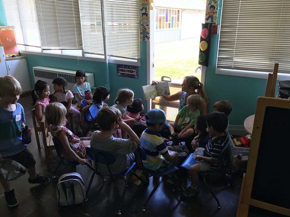 a young girl teaches a group of small children in a classroom