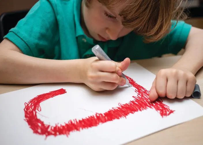 A boy tracing a letter.