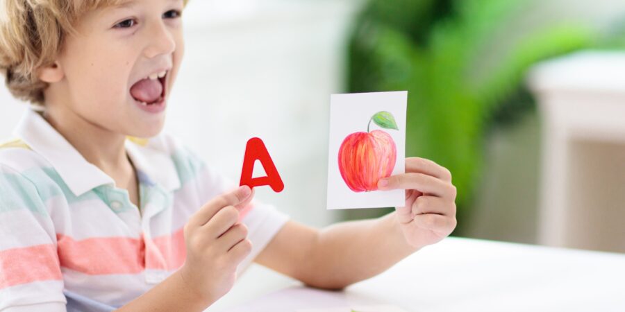 How to teach phonics to preschoolers. A boy with phonics cards. "A" is for "Apple."