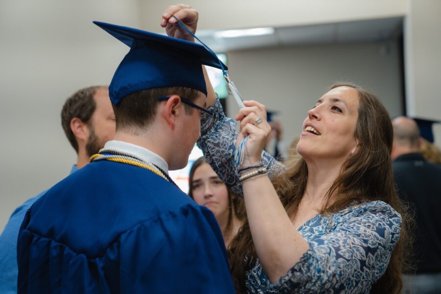 A homeschool mom fixing the tassel on her son's graduation cap