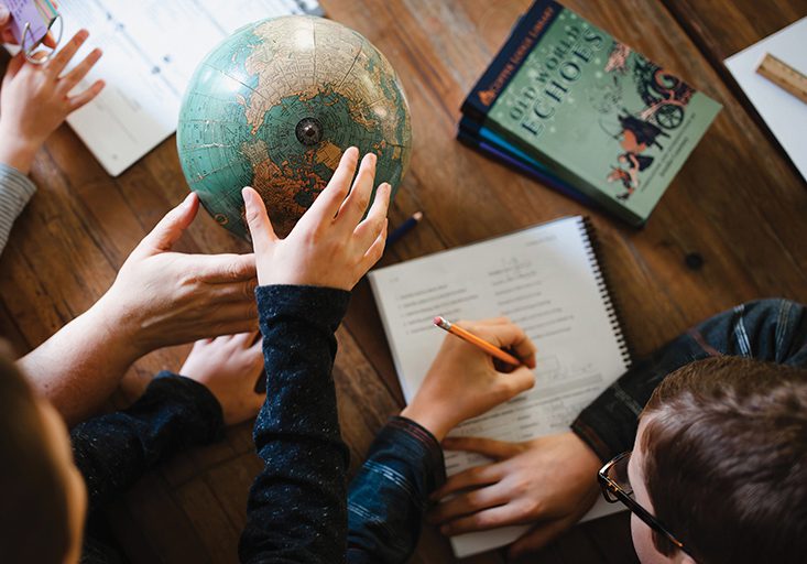overhead shot of students looking at a globe and reading a book from The Copper Lodge Library