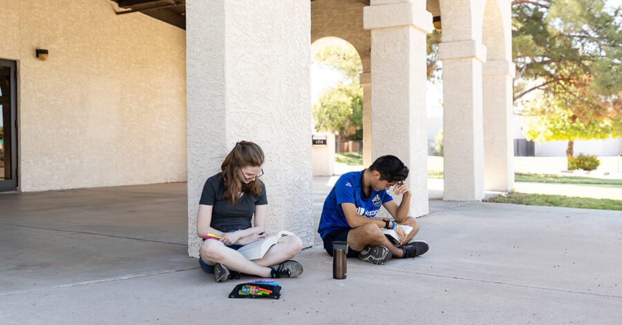 A girl and boy student sitting outside studying.