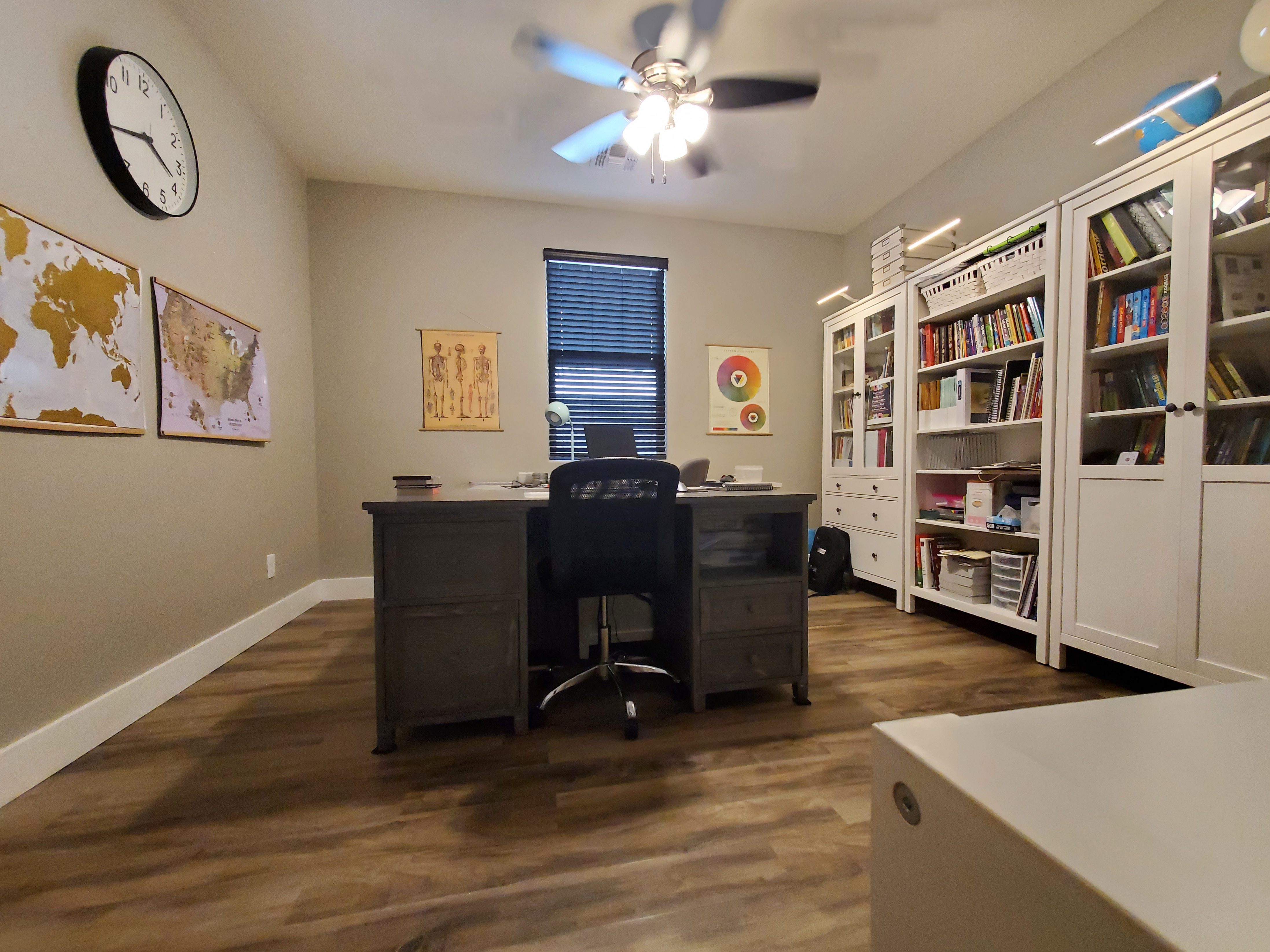 A homeschool room with maps and white bookcases.