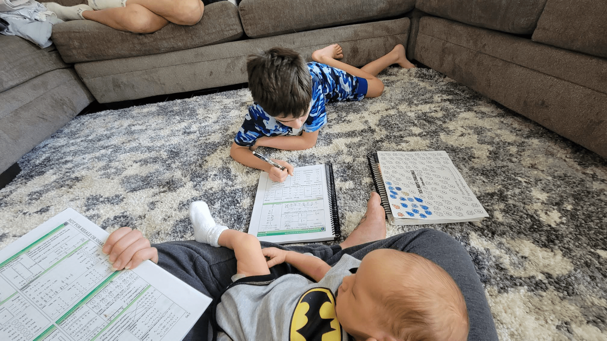 Doing homeschool on the floor with a boy and a baby.