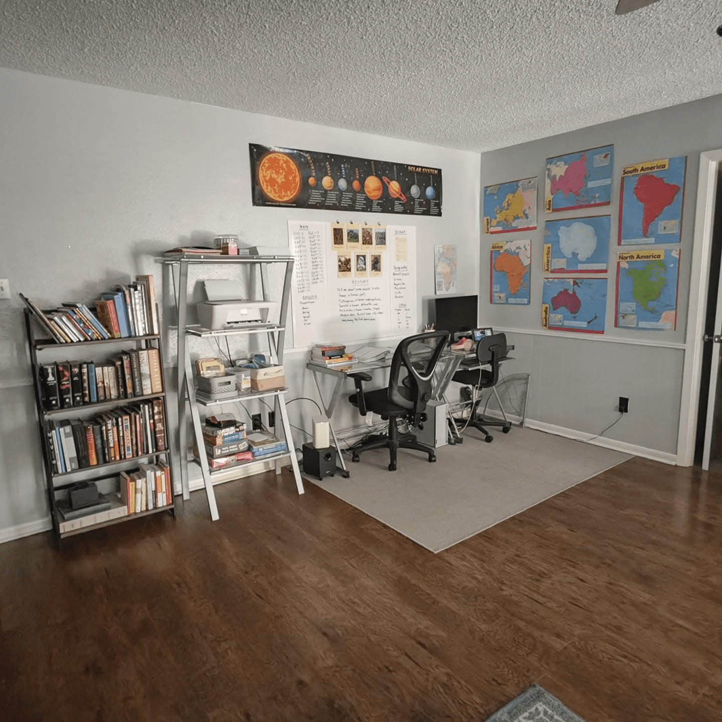 A homeschool station with maps, a computer desk, and bookshelves.