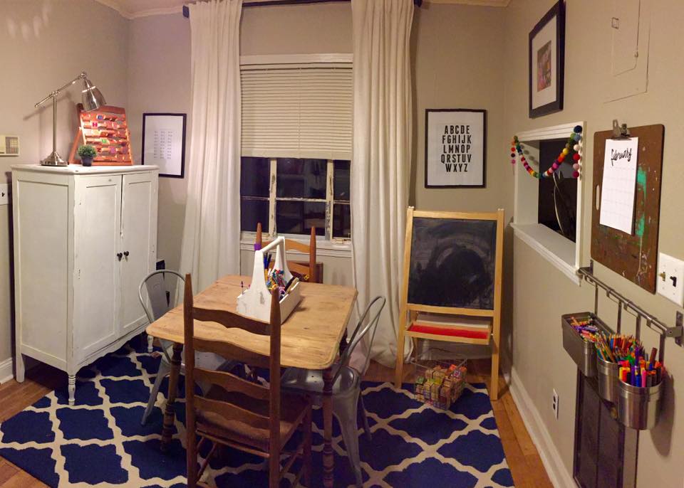 A homeschool room with a white cupboard and easel chalkboard.