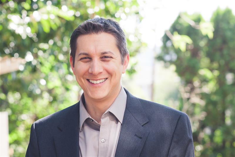 Man in a blazer smiling. Eliot Grasso, Vice President of Gutenberg College