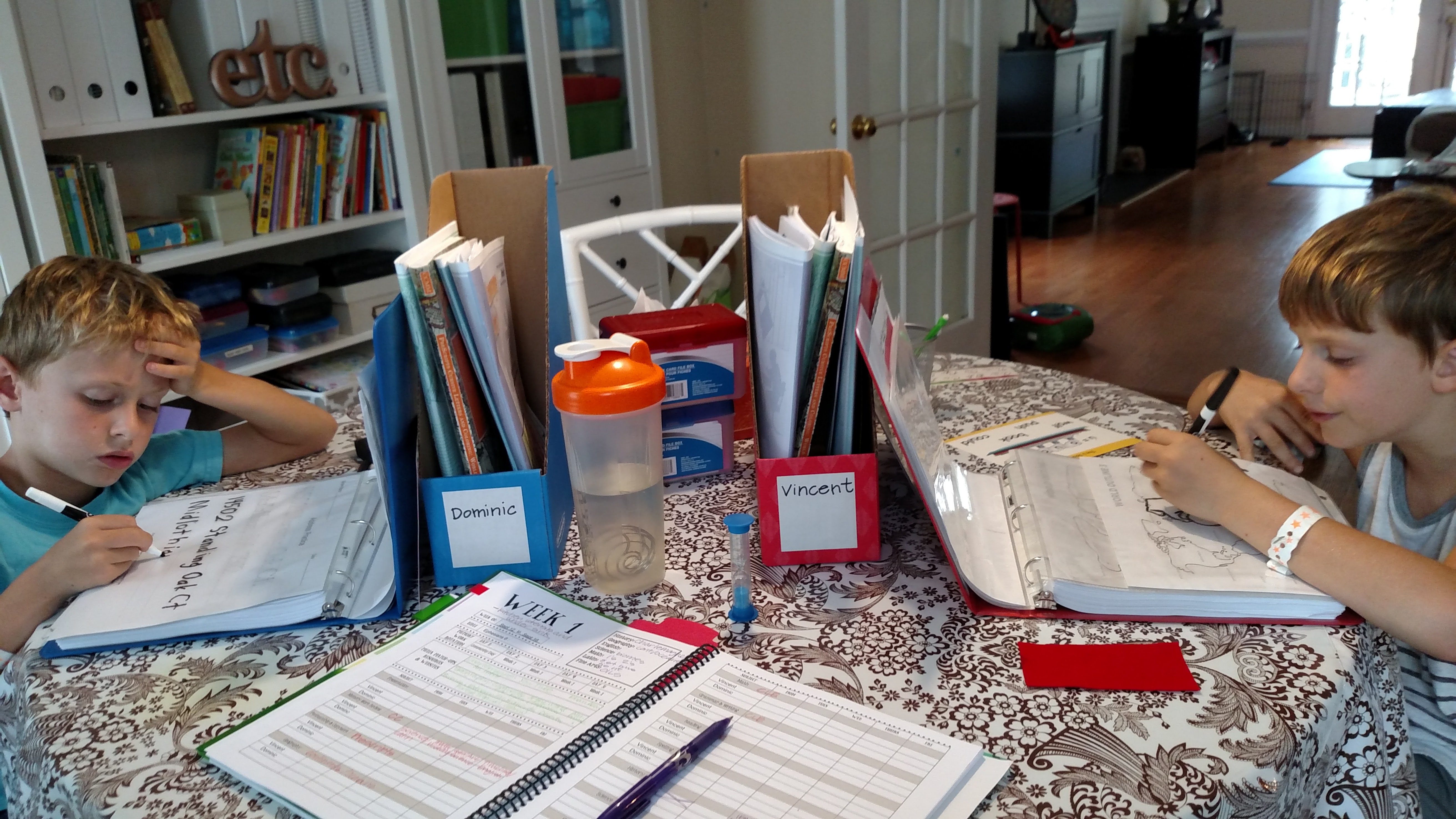 Two boys doing school work at the table together.