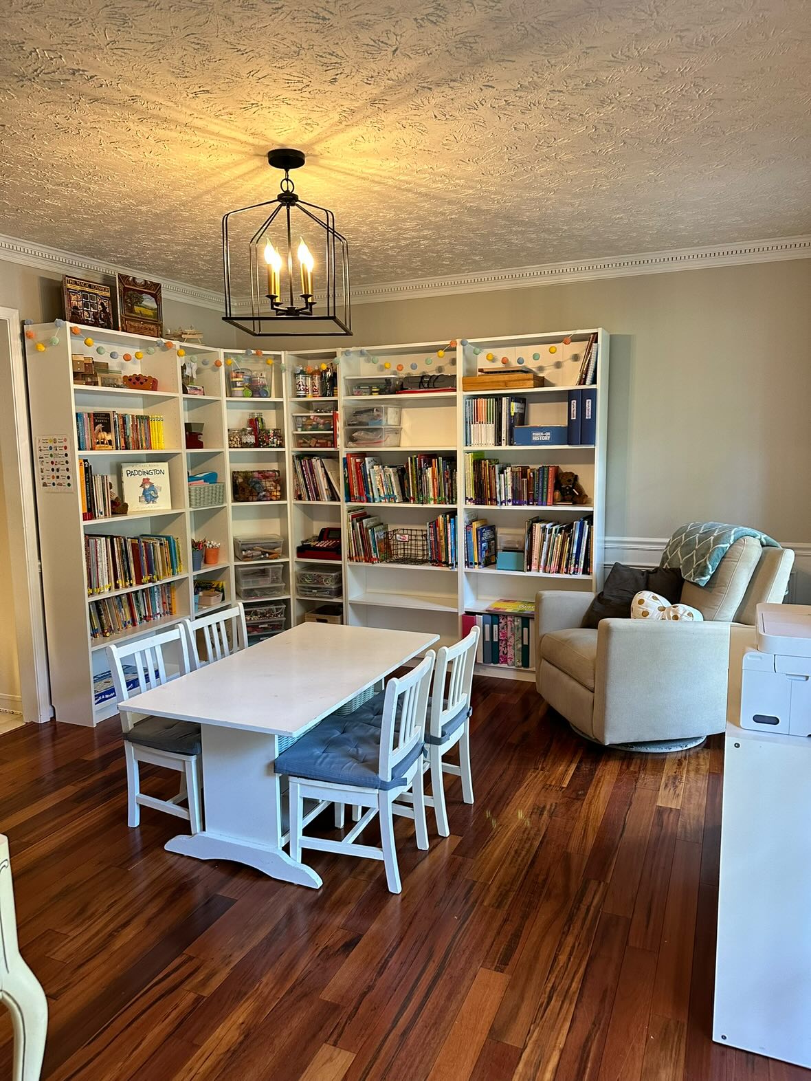 Homeschool corner with white bookcases and a little white table.