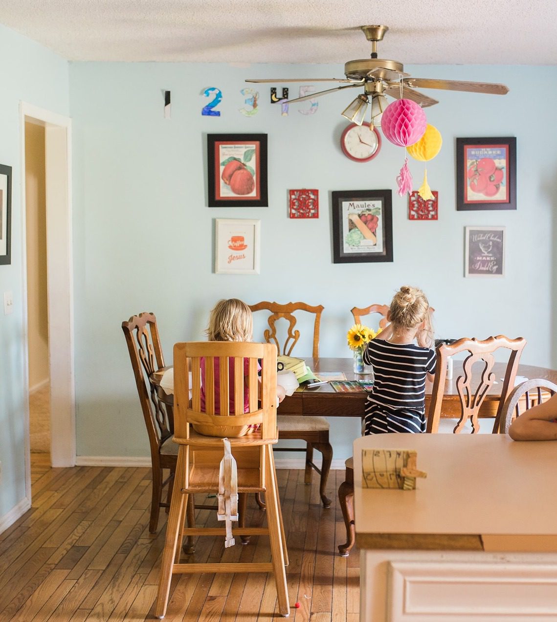 Two little girls doing homeschool crafts at the kitchen table.