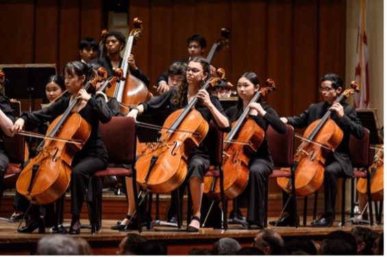 Homeschool student plays the cello in an orchestra.