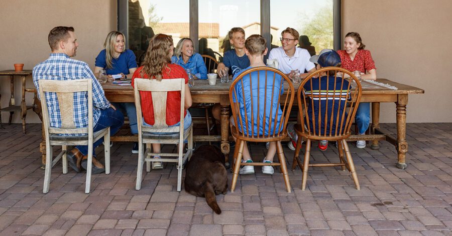 Homeschool families in community together sitting around a table talking