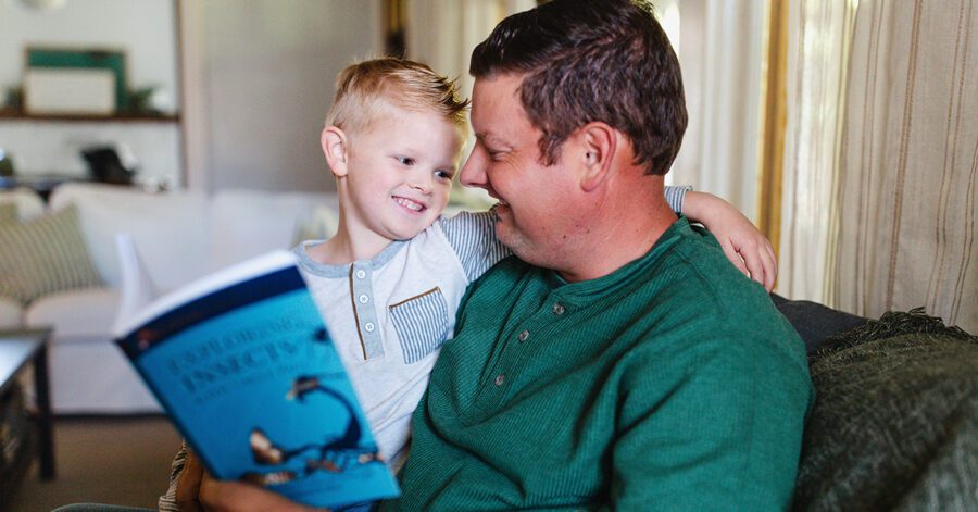A father and son sit together and do homeschool lessons
