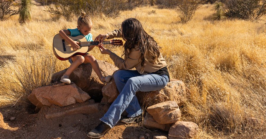 Homeschool parent teaching her child the 15 classical skills with a guitar.