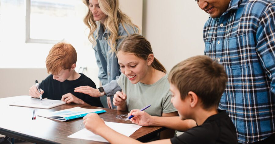 Homeschool students practicing the Christian math curriculum: The Math Map at a table with parents helping.
